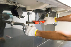 Plumber fixing sink pipe with wrench